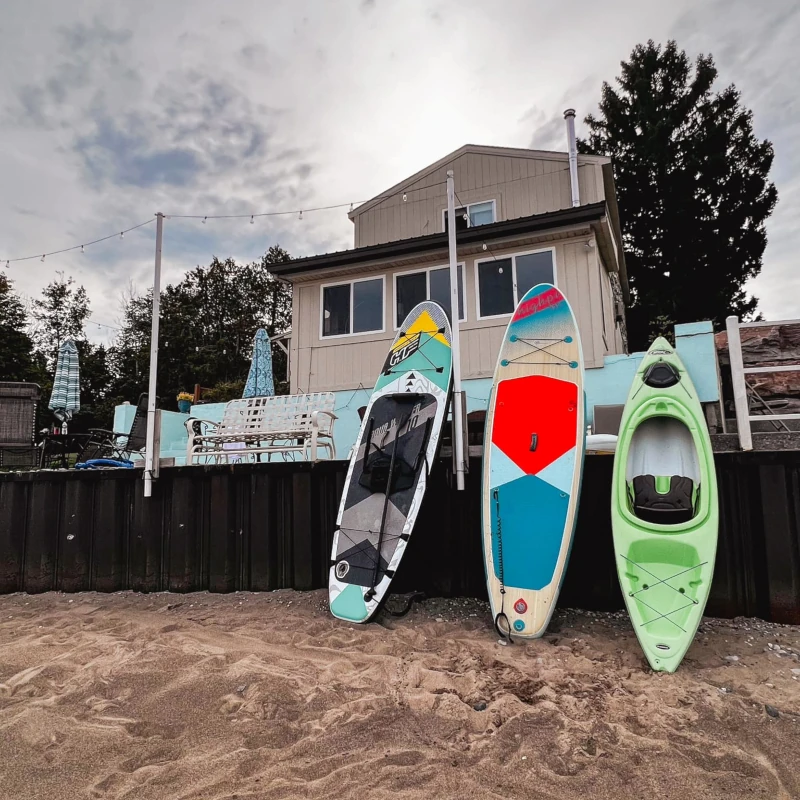 Sandy Lake Huron beach with kayaks and paddle-boards propped against the patio over which Hunsberger House rises