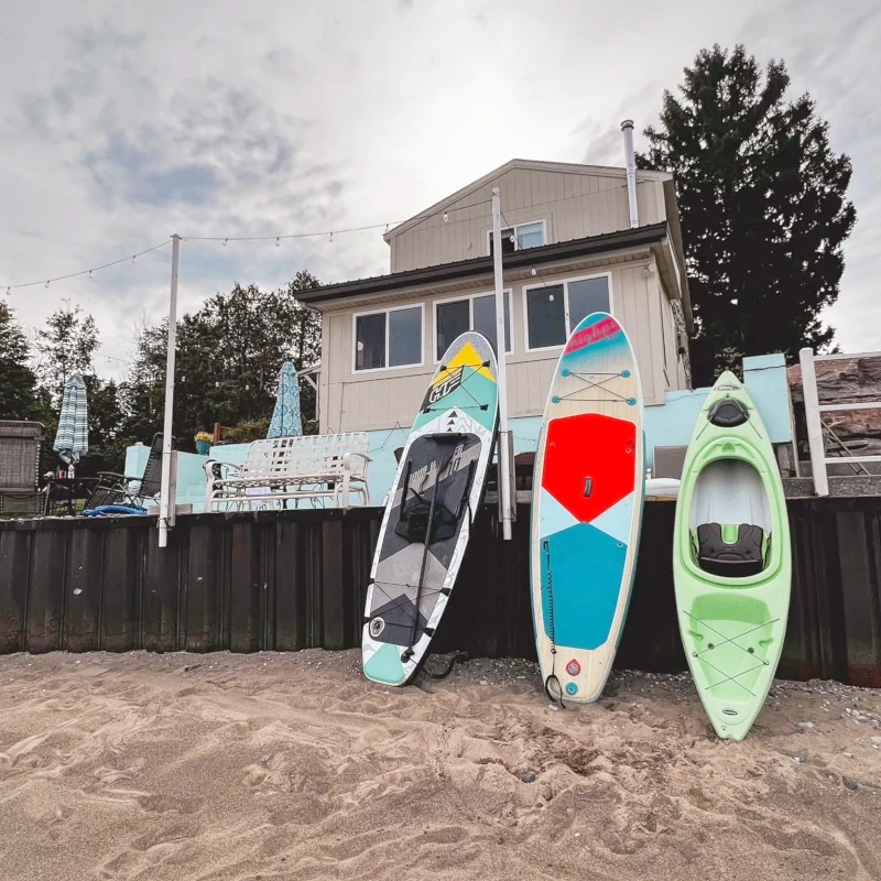 Sandy Lake Huron beach with kayaks and paddle-boards propped against the patio over which Hunsberger House rises.
